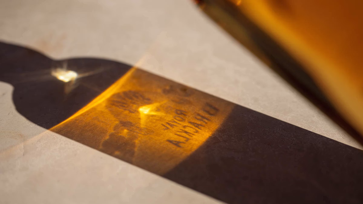 Royal Brackla bottle casting amber light and shadow on textured surface below.